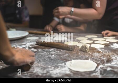 Wooden rolling pin and portioned flat dough which will be used for the making of traditional chinese dumplings during cooking class in a travellers ho Stock Photo