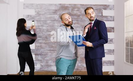 Real estate agent talking with client in empty apartment. Woman taking pictures in empty apartment. Stock Photo