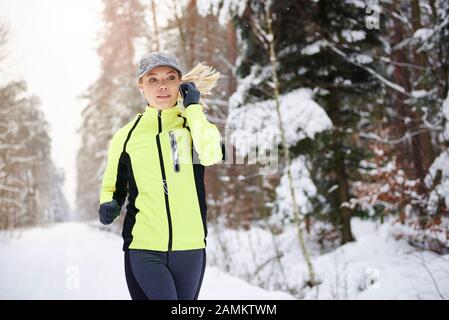 Woman listening to music and running in winter time Stock Photo