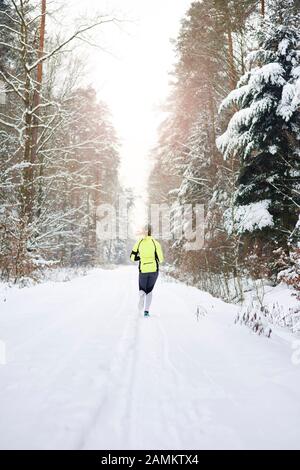 Rear view of woman running in winter forest Stock Photo
