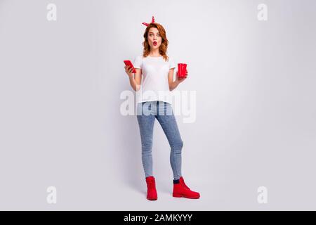 Full length body size view of her she nice attractive cheerful amazed glamorous girl holding in hand punch cup drinking beverage using 5g post Stock Photo