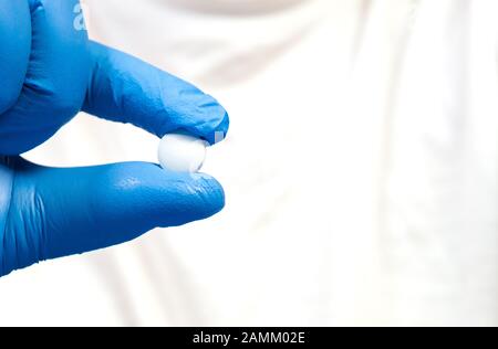 a woman's hand in a blue latex glove holds a pill, diseases colds, flu children's and adult colds. Stock Photo