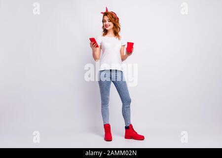 Full length body size view of her she nice attractive lovely cheerful cheery girl holding in hand punch cup using device spending free time weekend Stock Photo