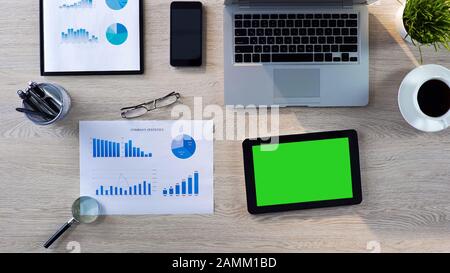 Top view of office workplace, tablet with green screen lying on the table, app Stock Photo