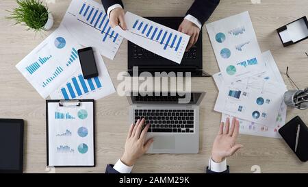 Hands of colleagues working on laptops, discussing company statistics, top view Stock Photo