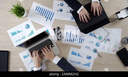 Two corporate employees typing on laptops, working on business project, top view Stock Photo