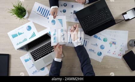 Company employees discussing statistics together, sharing opinions, top view Stock Photo
