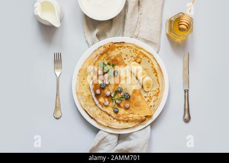 Crepes, thin russian pancakes on white plate. Pastel blue background. Top view. Space for text. Stock Photo
