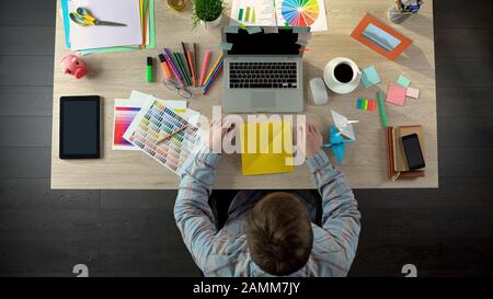 Creative man making origami cranes to calm down, meditating on ideas, top view Stock Photo