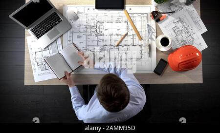 Architect checking notes making in his notebook to add it to drawing of building Stock Photo