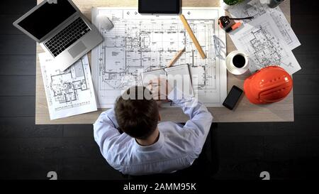 Architect checking drawing of building, making notes to discuss with colleagues Stock Photo
