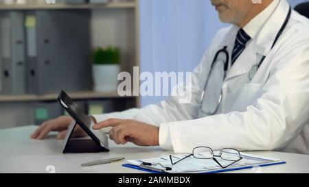 Therapist checks electronic medical records on tablet, technologies, healthcare Stock Photo