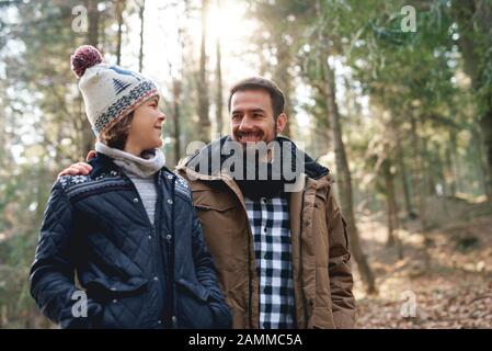 Happy dad and teenage son walking in the autumn forest Stock Photo