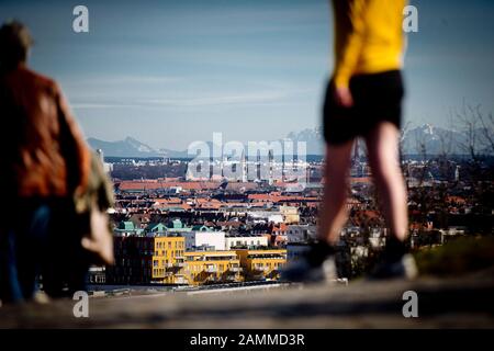 Spring in Munich's Olympic Park: the picture shows the view from the Olympic mountain Ludwigskirche.with the Frauenkirche. In the foreground a jogger, in the background the alpine chain. [automated translation] Stock Photo