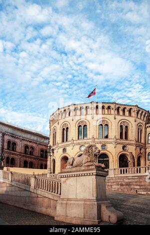 A fragment of the architecture of the Norwegian Parliament building on Eidsvolls square. The figure of a lion sits on a pedestal. Small clouds are bea Stock Photo