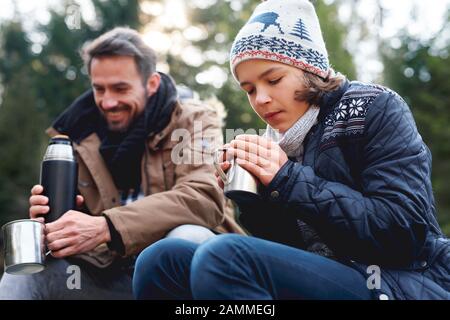 Teenage boy drinking hot tea in autumn forest Stock Photo