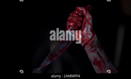 Mad serial killer gripping knife covered in blood, hands of ruthless maniac Stock Photo