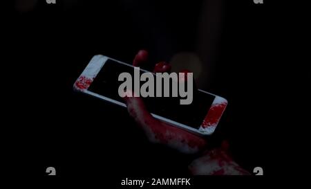 Hopeless victim looking at broken smartphone in hands, fear and horror, accident Stock Photo
