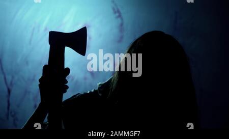 Possessed woman holding bloody ax and looking at victim, nightmarish scene Stock Photo
