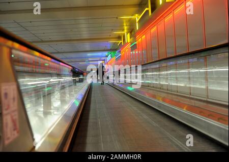 Air passengers on a moving walkway under Terminal 1 at Munich Airport. [automated translation] Stock Photo