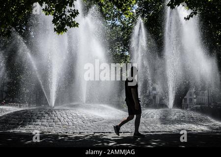 A passer-by in front of the fountains of the fountain at the Sendlinger Tor in the midday sun. [automated translation] Stock Photo