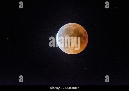 Full moon during a total shadow eclipse over Munich. The moon enters completely into the earth's shadow, only long-wave red light components reach it and it remains weakly visible as a so-called blood moon. [automated translation] Stock Photo