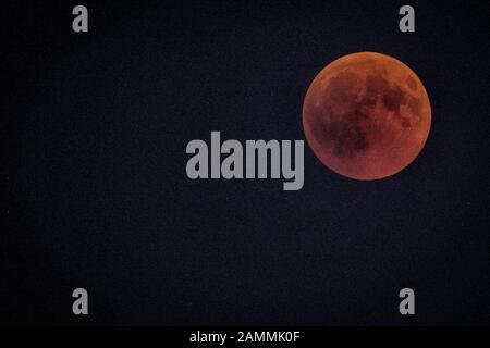 Full moon during a total shadow eclipse over Munich. The moon enters completely into the earth's shadow, only long-wave red light components reach it and it remains weakly visible as a so-called blood moon. [automated translation] Stock Photo