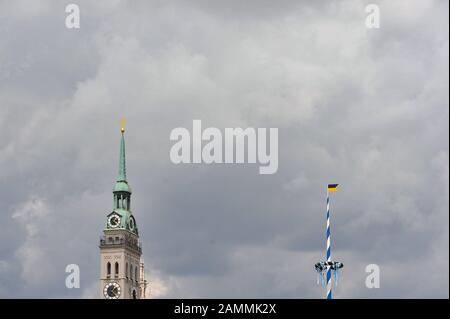 The tower of the parish church St. Peter and the maypole on the Munich Viktualienmarkt against a cloudy sky. [automated translation] Stock Photo