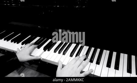 Female hands playing piano, concert of classical music, black and white closeup Stock Photo