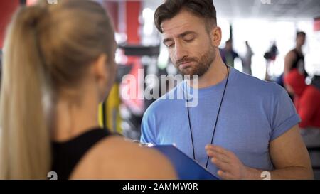 Trainer supervising client workout program and giving useful advice on training Stock Photo