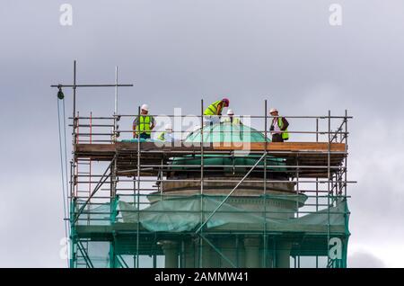 Construction workers working on green copper dome of St Stephen's church, Dublin, Ireland. People wearing safety helmets / hard hats at scaffold tower Stock Photo