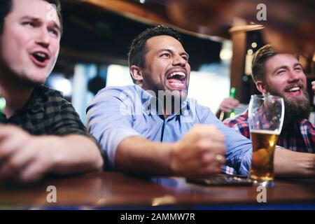 Excited football fans watching american football in the pub Stock Photo