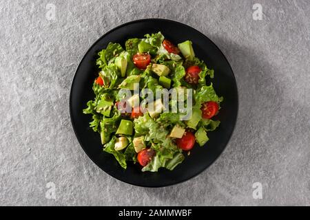 Salad with avocado, lettuce, tomato and flax seeds on gray background. Top view. Stock Photo