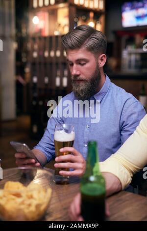 Hipster man using mobile phone and drinking beer Stock Photo