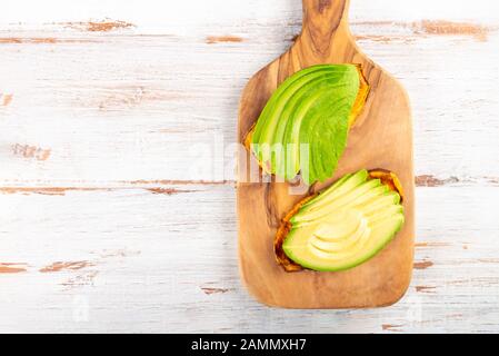 Sweet potato toasts with avocado on wooden board. Healthy meal concept. Clean eating, vegetarian food, top view Stock Photo