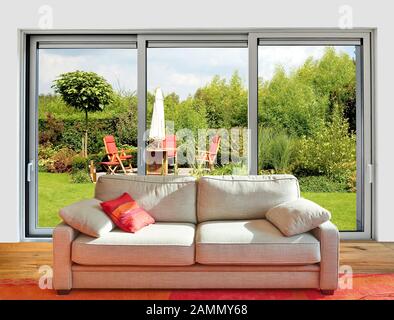 Elegant classical Sofa from front with great windows and view on lush garden Stock Photo