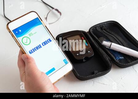 Measuring glucose levels and using smart phone. Healthcare and medical concept Stock Photo