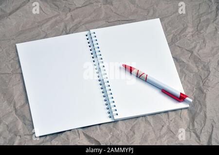 A pen on a blank notebook on a background of crumpled beige packaging. Stock Photo