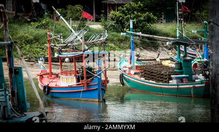 Thai fishing boats tied up to each other in the harbor of Ben Krut with reflections in the water Stock Photo
