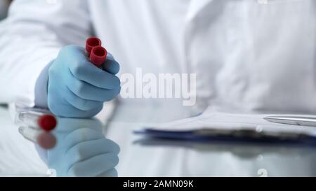 Lab assistant analyzing test tubes with viruses for filling database report Stock Photo