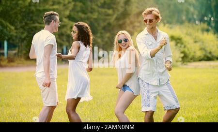 Two cute couples hanging out at open-air festival, dancing to music, having fun Stock Photo