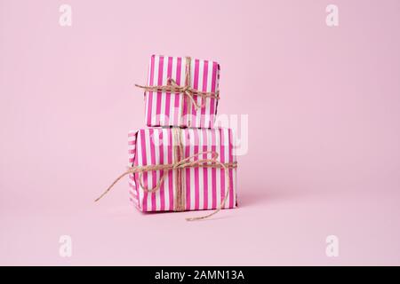 two boxes wrapped in pink paper and tied with a brown rope on a pink background, holiday backdrop Stock Photo