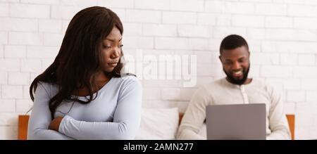 Couple Crisis. Man Using Laptop, Not Paying Attention To Wife Stock Photo