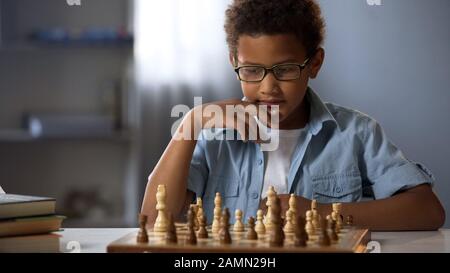 Concentrated boy developing chess strategy, playing board game with friend Stock Photo