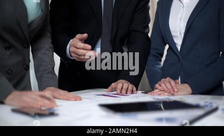 Male boss giving advice to female managers working on investment plan Stock Photo