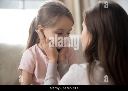 Loving young mother touching upset little daughter face, supporting Stock Photo