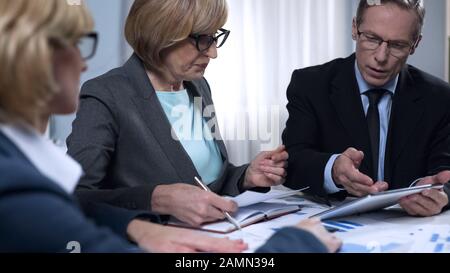 Scientists comparing graphics of population growth with tablet data in office Stock Photo