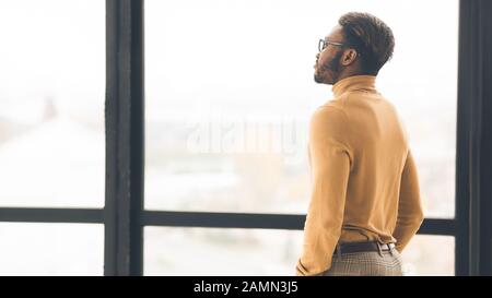 Single afro businessman looking out the window Stock Photo
