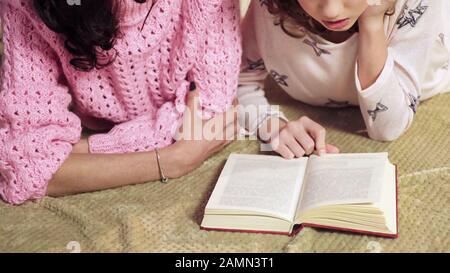 Mom checking daughters homework on literature, parents as tutors, homeschooling Stock Photo