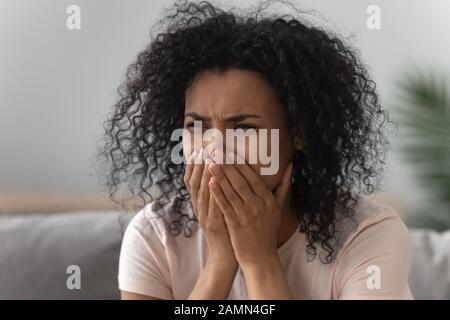 Grieving african woman crying sitting on couch Stock Photo